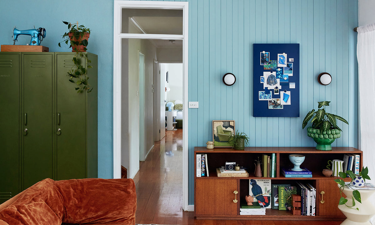 A living room with Ocean blue paneled walls, three Skinny lockers in Olive and a Navy Storyboard pinboard, styled in a 60-30-10 color palette