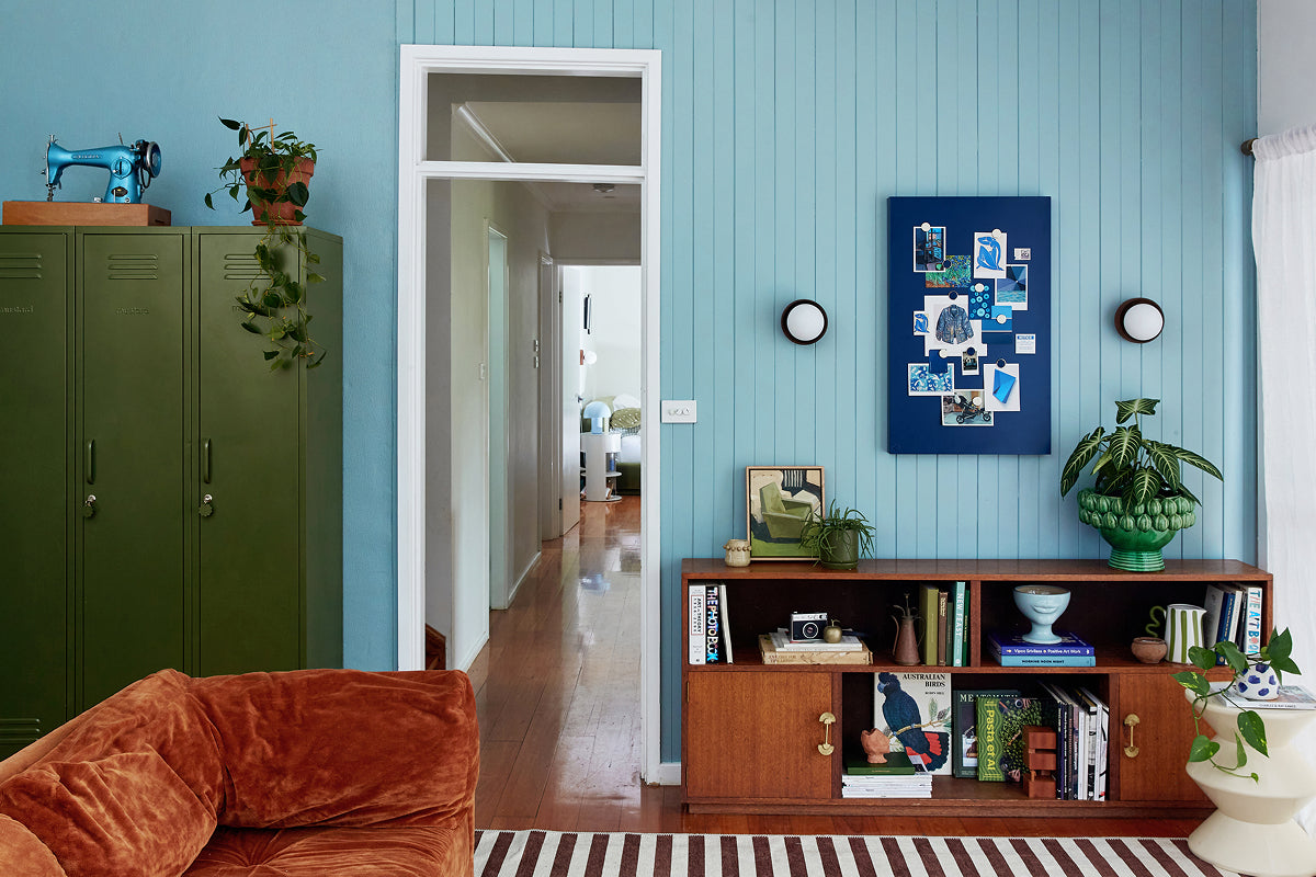 A living room with Ocean blue paneled walls, three Skinny lockers in Olive and a Navy Storyboard pinboard, styled in a 60-30-10 color palette