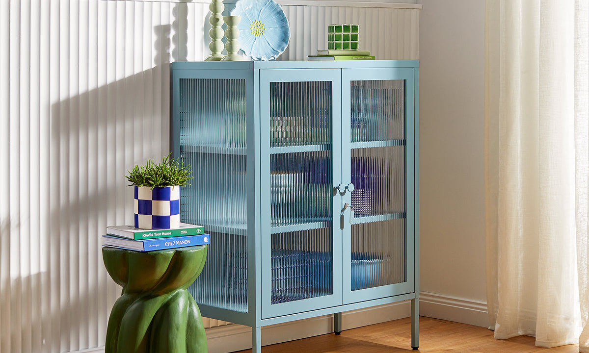 Mustard Made's The Mixer glass cabinet in Ocean, a pale dusty blue, styled with ceramics against fluted wall paneling