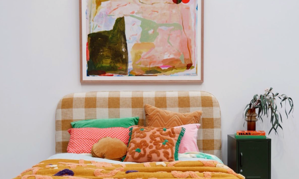 Colorful artwork hanging above a bed, a Mustard Made locker is beside the bed.