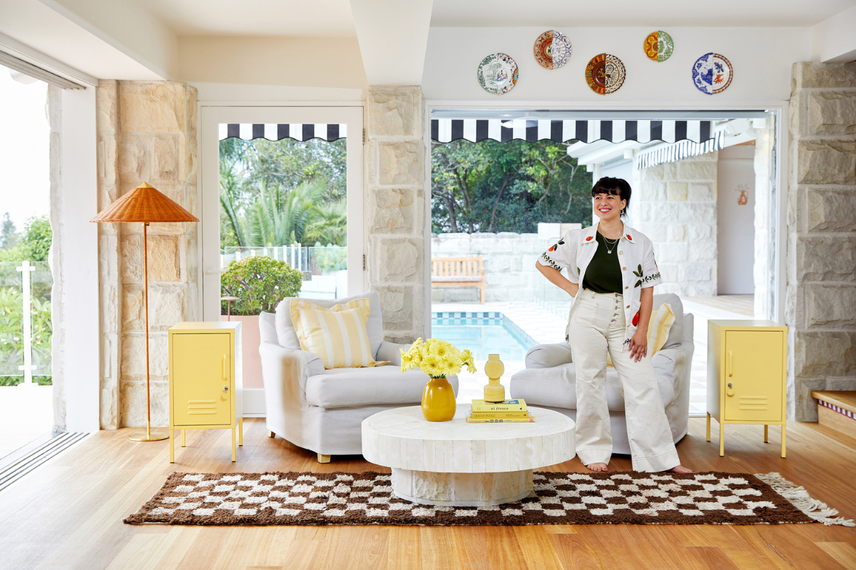 Becca stands in a beautifully styled home with two Butter Shortys either side of her. There is a pool outside in the background.