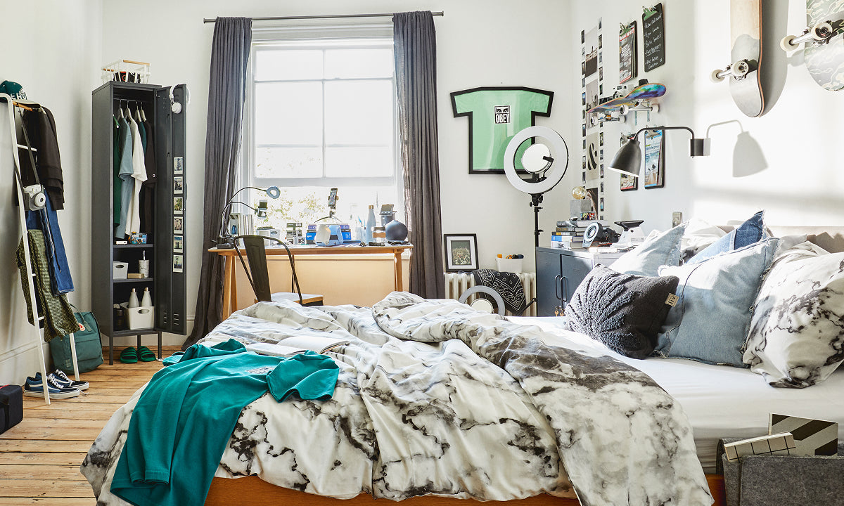 The Skinny locker in Slate, open as a wardrobe in a dorm room with a desk by the window and skateboards on the wall