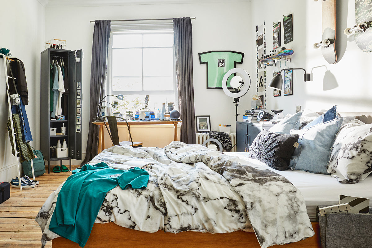 The Skinny locker in Slate, open as a wardrobe in a dorm room with a desk by the window and skateboards on the wall